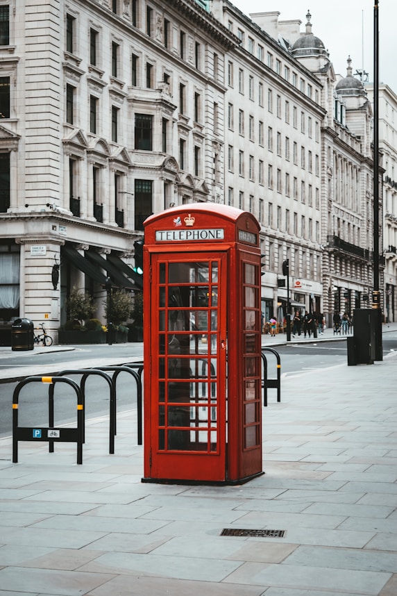 red telephone booth near white concrete building during daytime