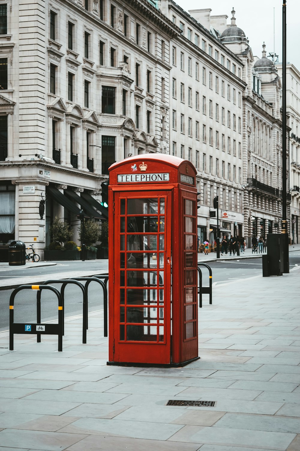 Cabina telefonica rossa vicino all'edificio in cemento bianco durante il giorno