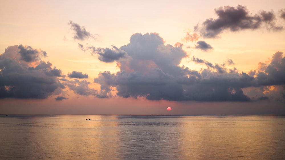 body of water under cloudy sky during sunset