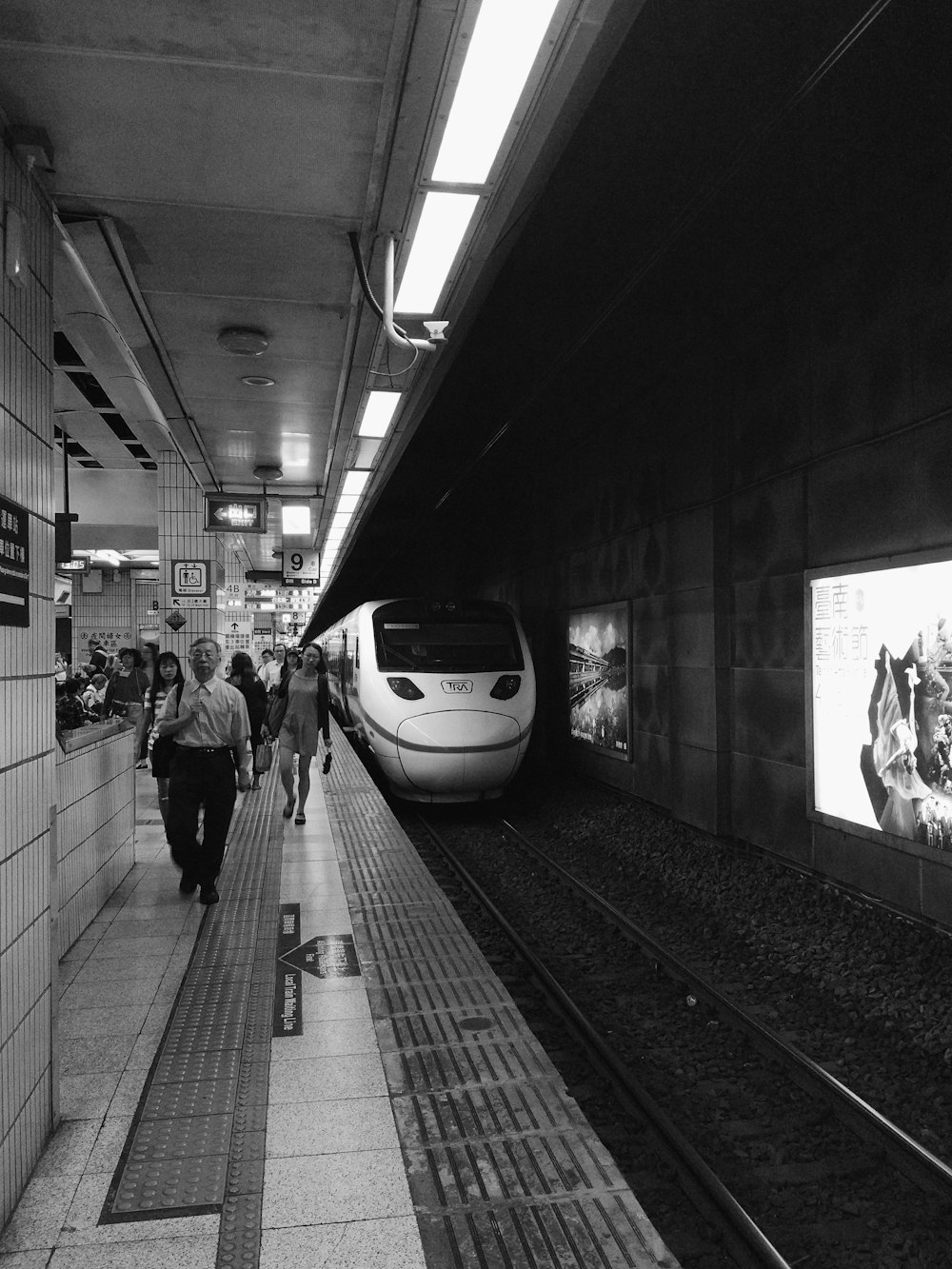 grayscale photo of people in train station