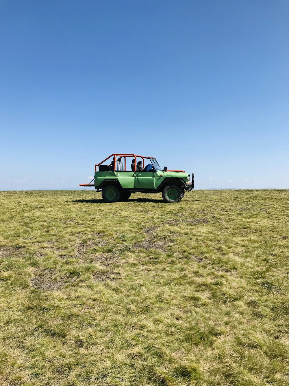 green and white car on green grass field under blue sky during daytime