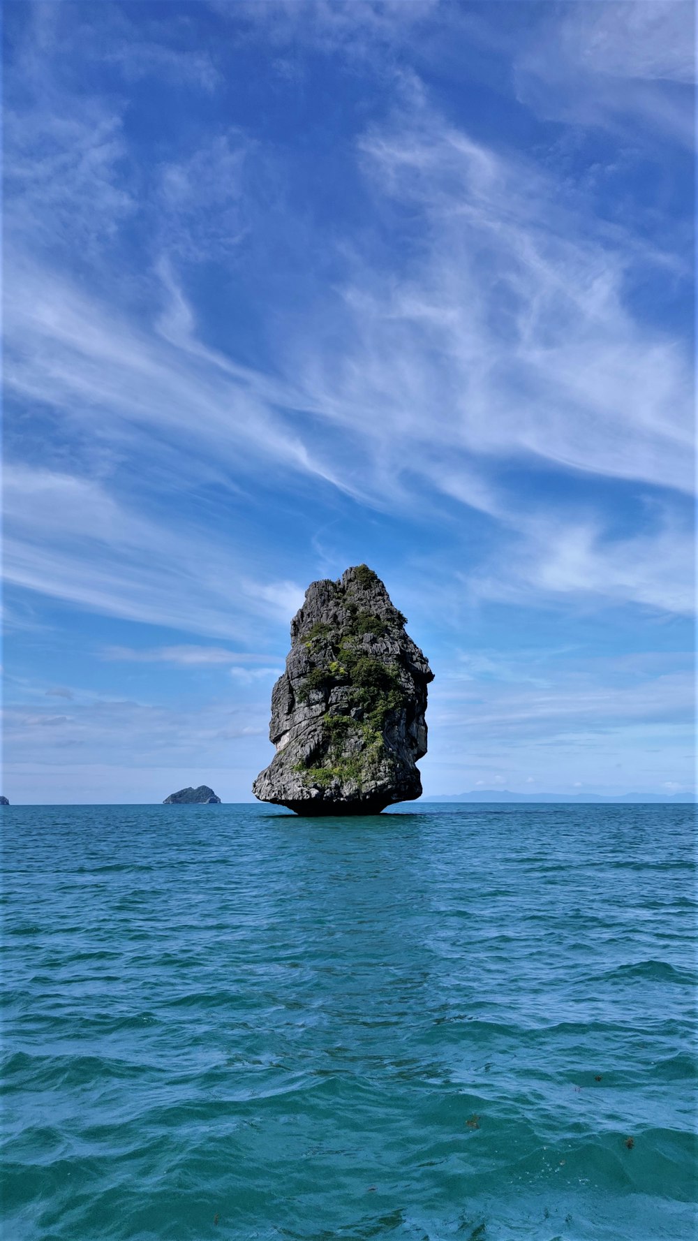 gray rock formation on blue sea under blue sky during daytime