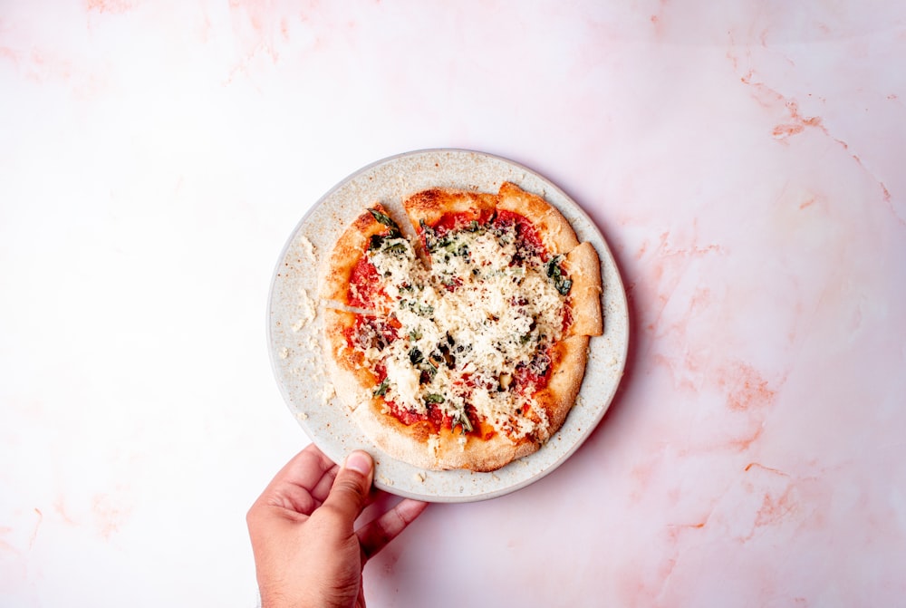 person holding pizza with cheese