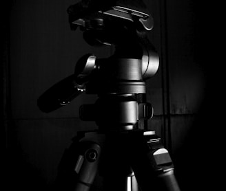black camera on tripod in grayscale photography