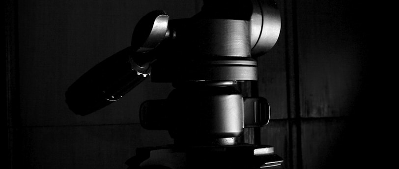 black camera on tripod in grayscale photography