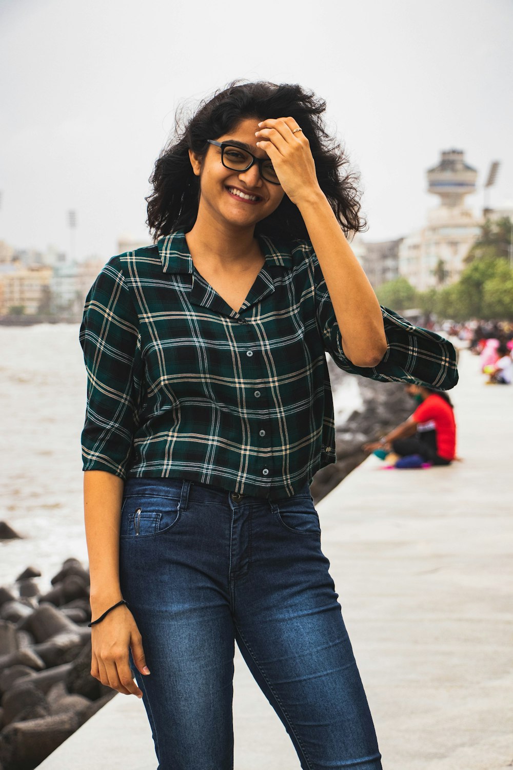 woman in black and white checkered button up shirt and blue denim jeans standing on beach