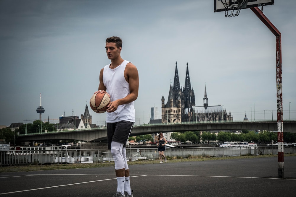 man in orange tank top and white pants holding basketball