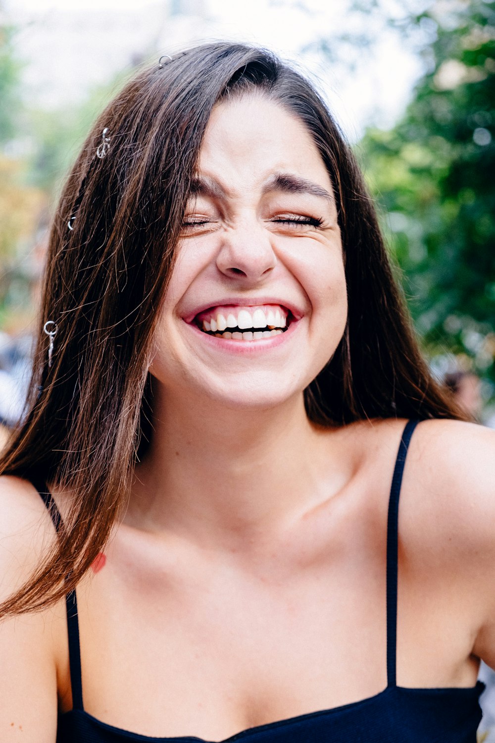 femme en haut à bretelles spaghetti noires souriant