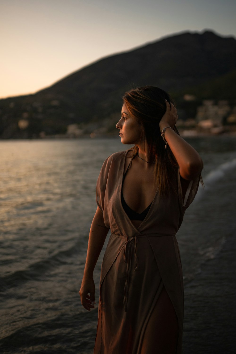 woman in black spaghetti strap dress standing on seashore during daytime