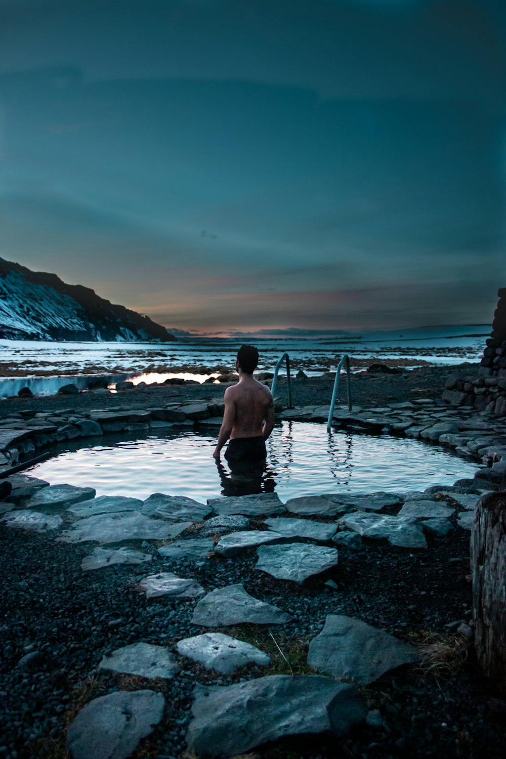 man in black shorts walking on rocky shore during daytime