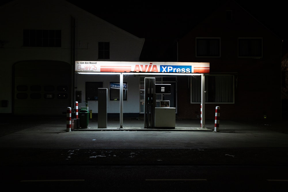 a gas station at night with a lit up sign