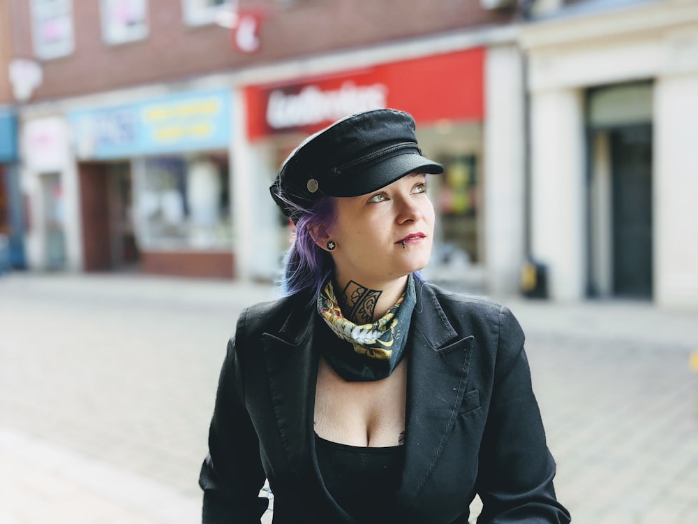 woman in black leather jacket and black hat standing on street during daytime