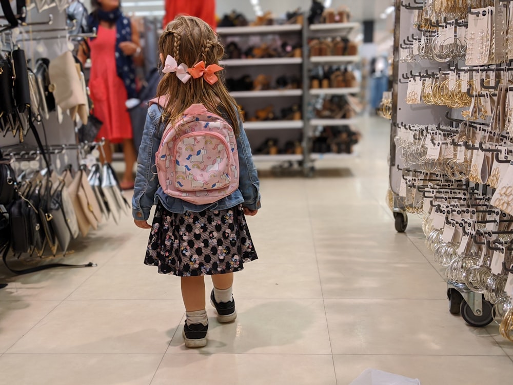 girl in pink and blue floral dress standing on white floor tiles