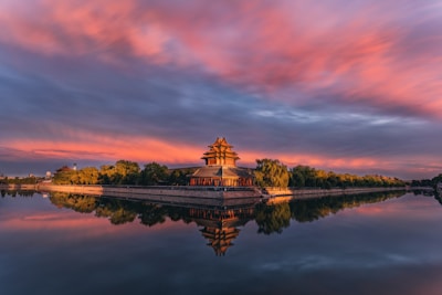 brown and white temple near body of water during sunset
