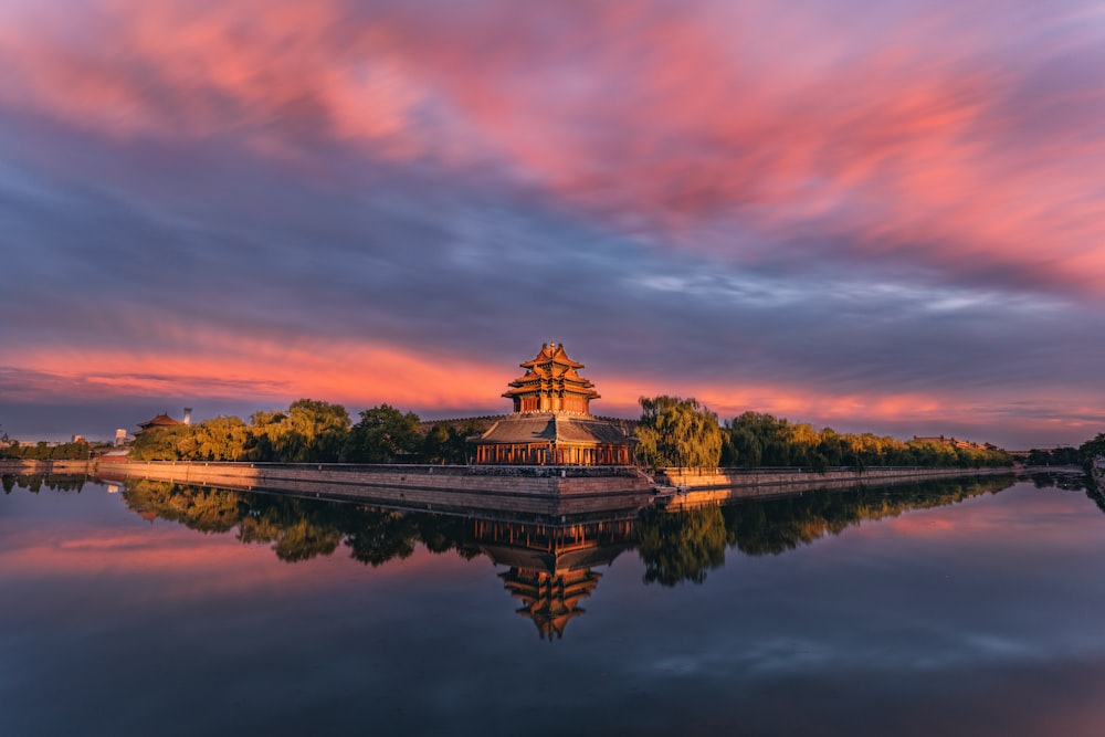 Temple brun et blanc près du plan d’eau au coucher du soleil