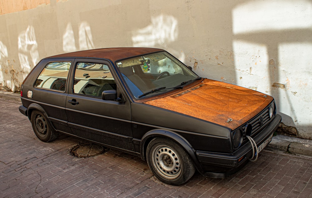 black and brown sedan parked beside white wall