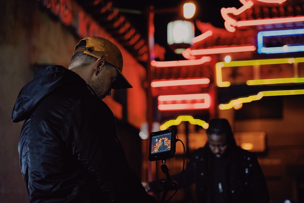 man in black jacket and yellow hard hat holding black camera