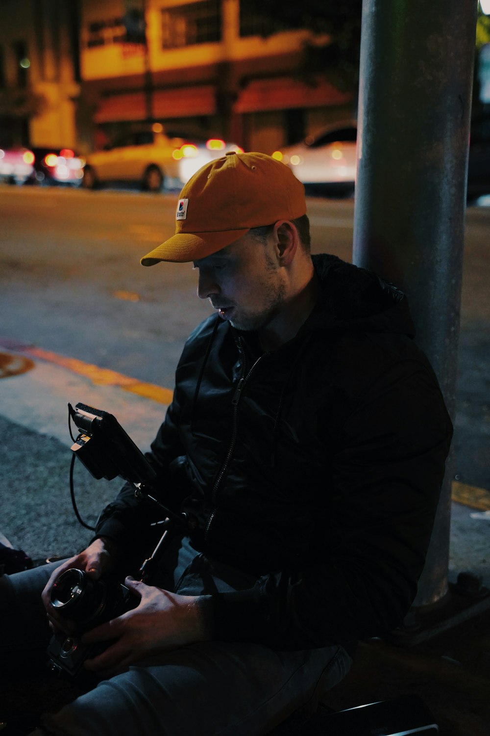 man in black jacket and orange cap sitting on black motorcycle