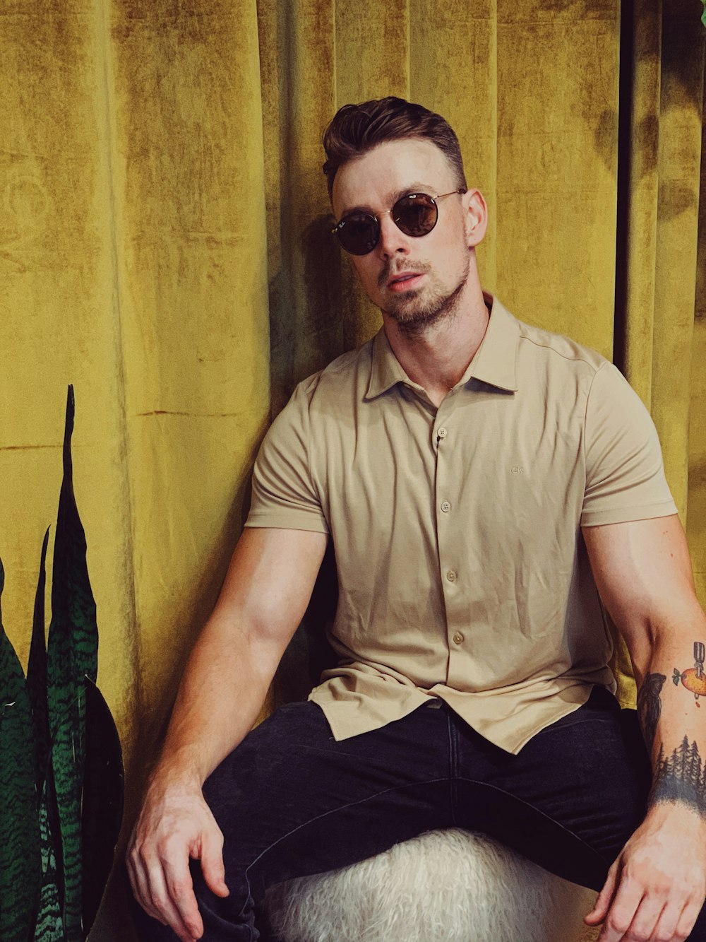 man in brown button up shirt and black pants wearing sunglasses sitting on chair