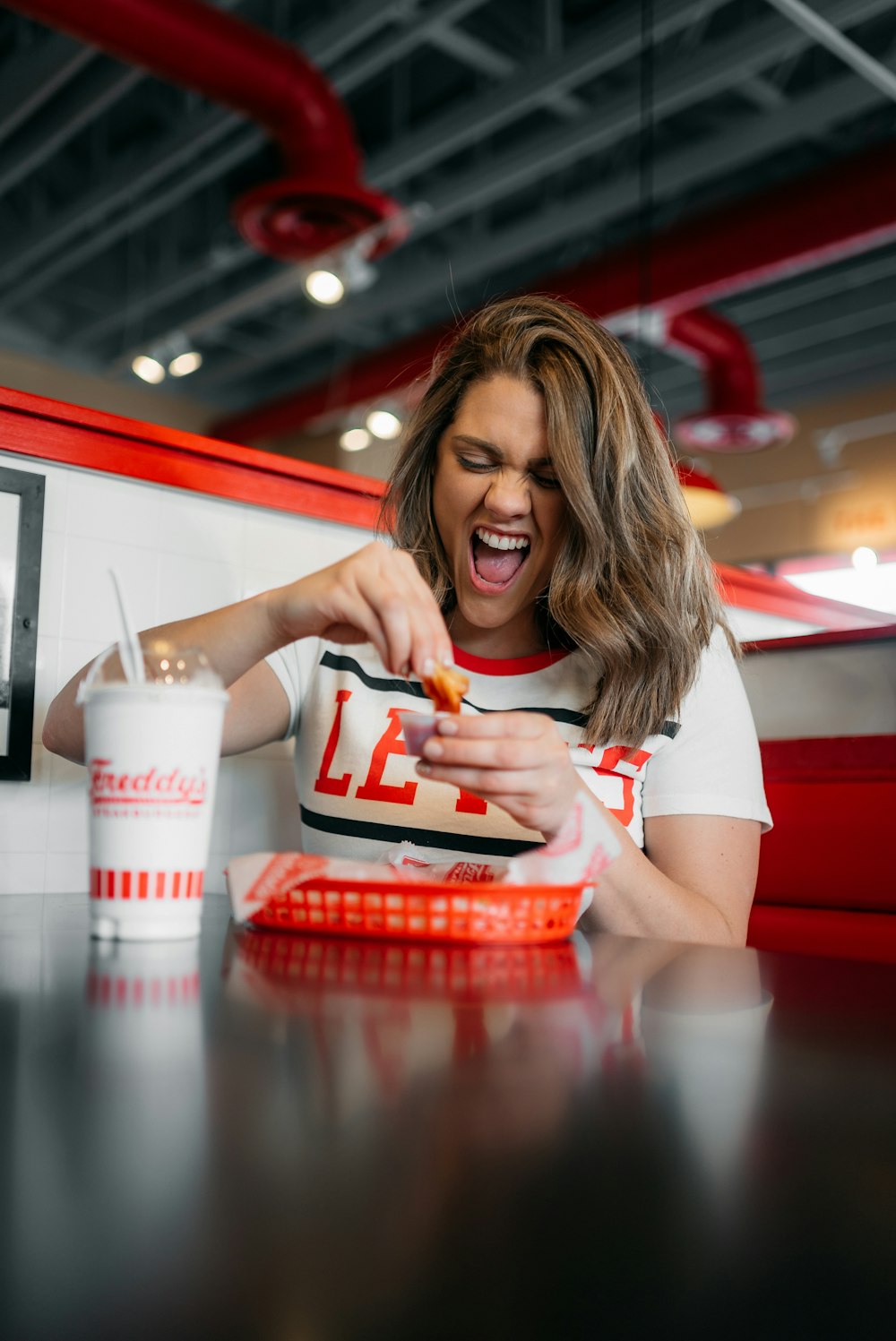 woman in white shirt holding red and white plastic container