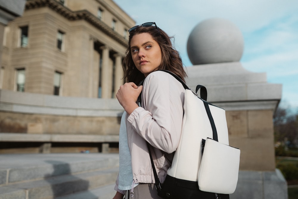 woman in white blazer holding white leather handbag