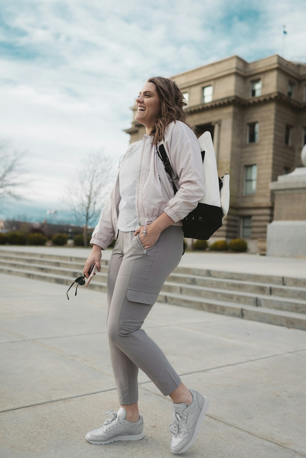 woman in white blazer and gray pants standing on gray concrete floor during daytime