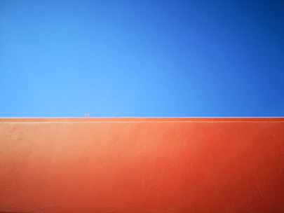 Freshly painted bright orange exterior wall of a modern North York home under a clear sky.