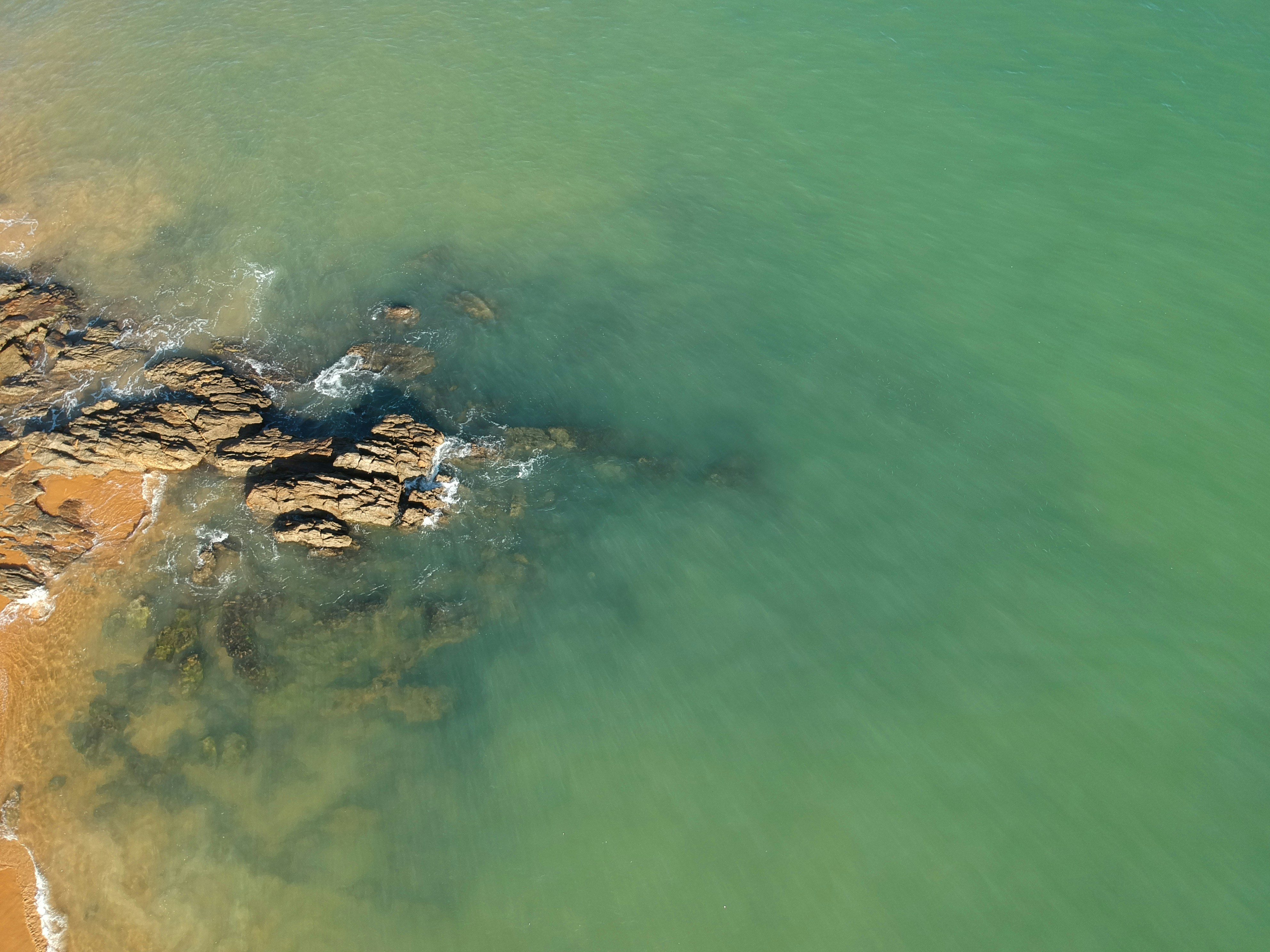brown rock formation on body of water during daytime
