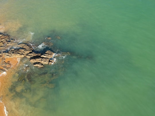 brown rock formation on body of water during daytime in Anchieta Brasil