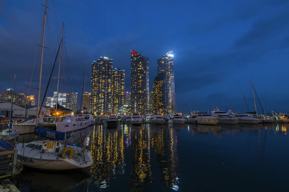 Serene harbor scene at night, boats reflected on calm water surface under warm lighting