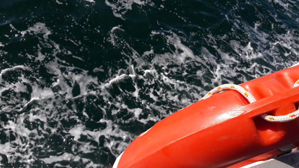 orange surfboard on body of water