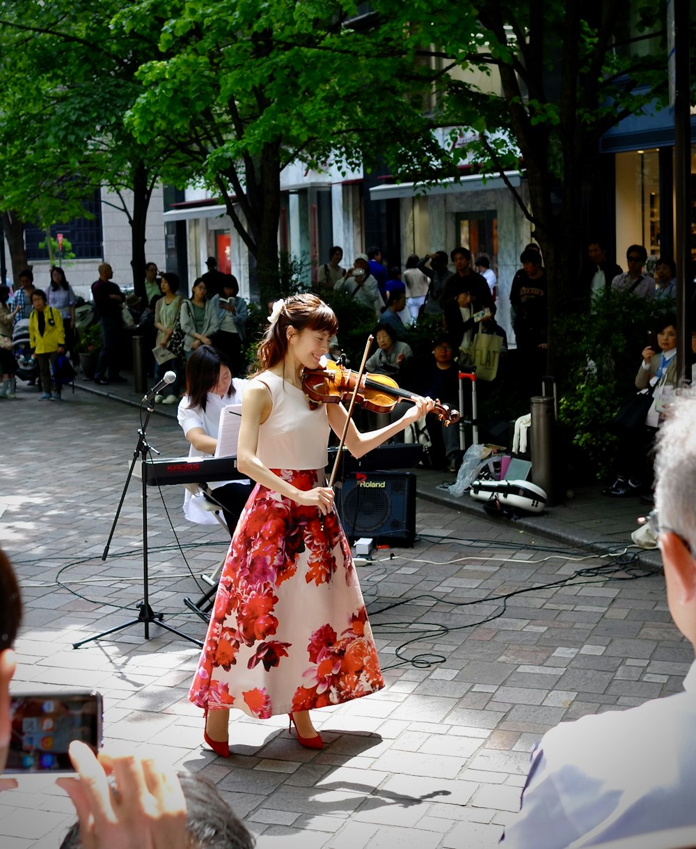 Frau in rot-weißem Blumenkleid spielt Geige