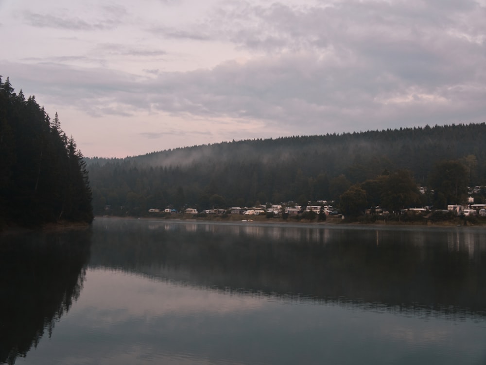 body of water near green trees under white clouds during daytime