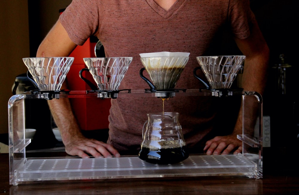 man in brown v neck t-shirt sitting beside table with drinking glasses