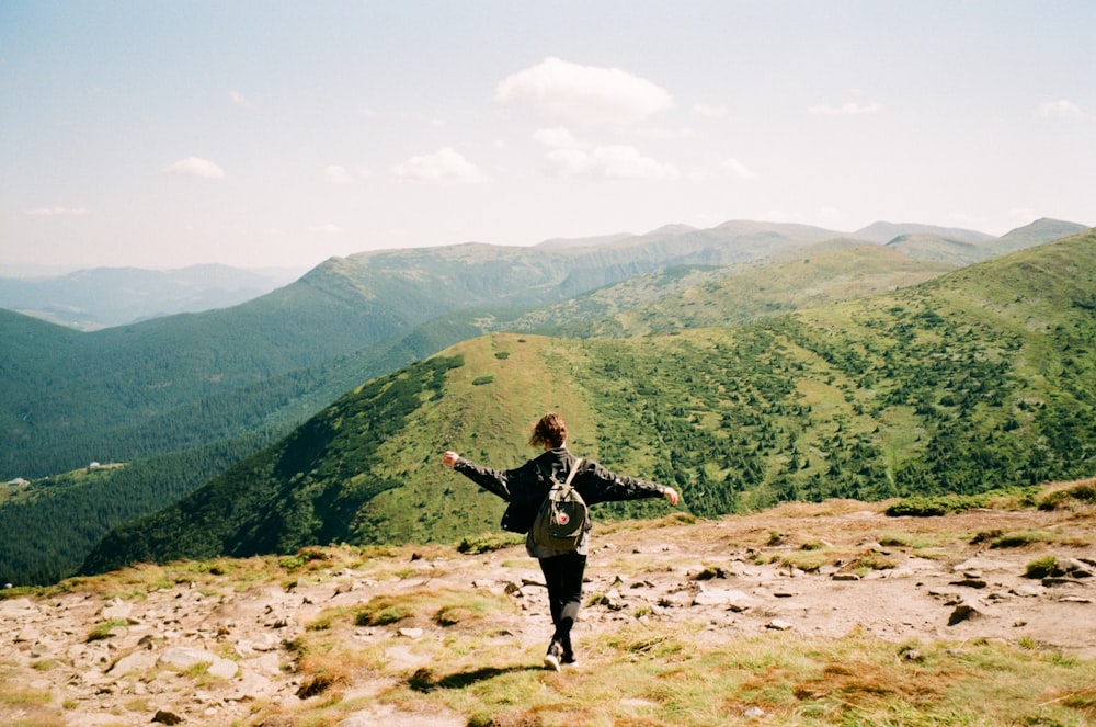 woman in black jacket standing on brown rock mountain during daytime