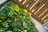 A vertical garden with a variety of lush green plants set against a modern wooden slat wall. The lighting casts a warm glow, highlighting the diversity and vibrancy of the foliage.