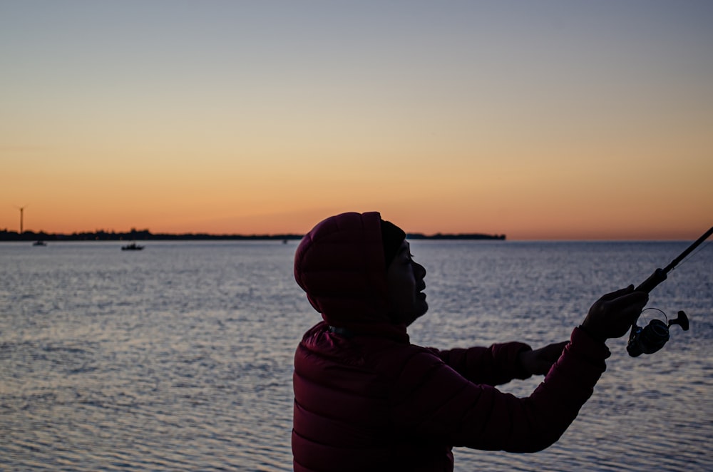silhouette d’une personne devant un plan d’eau au coucher du soleil