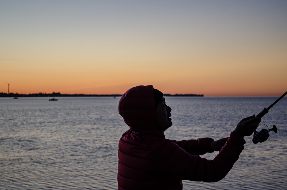 silhouette of person in front of body of water during sunset