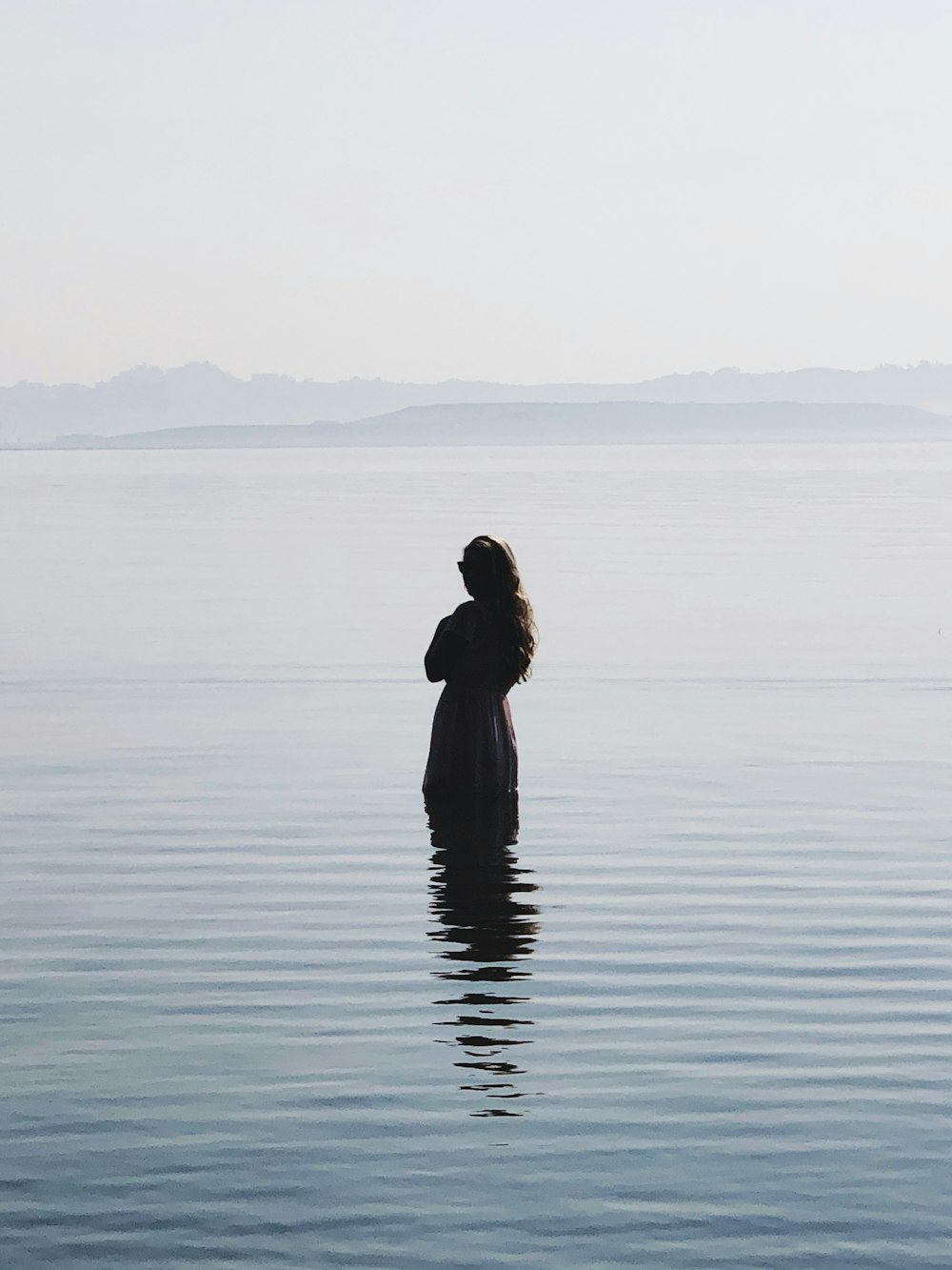 femme en robe noire debout sur l’eau pendant la journée