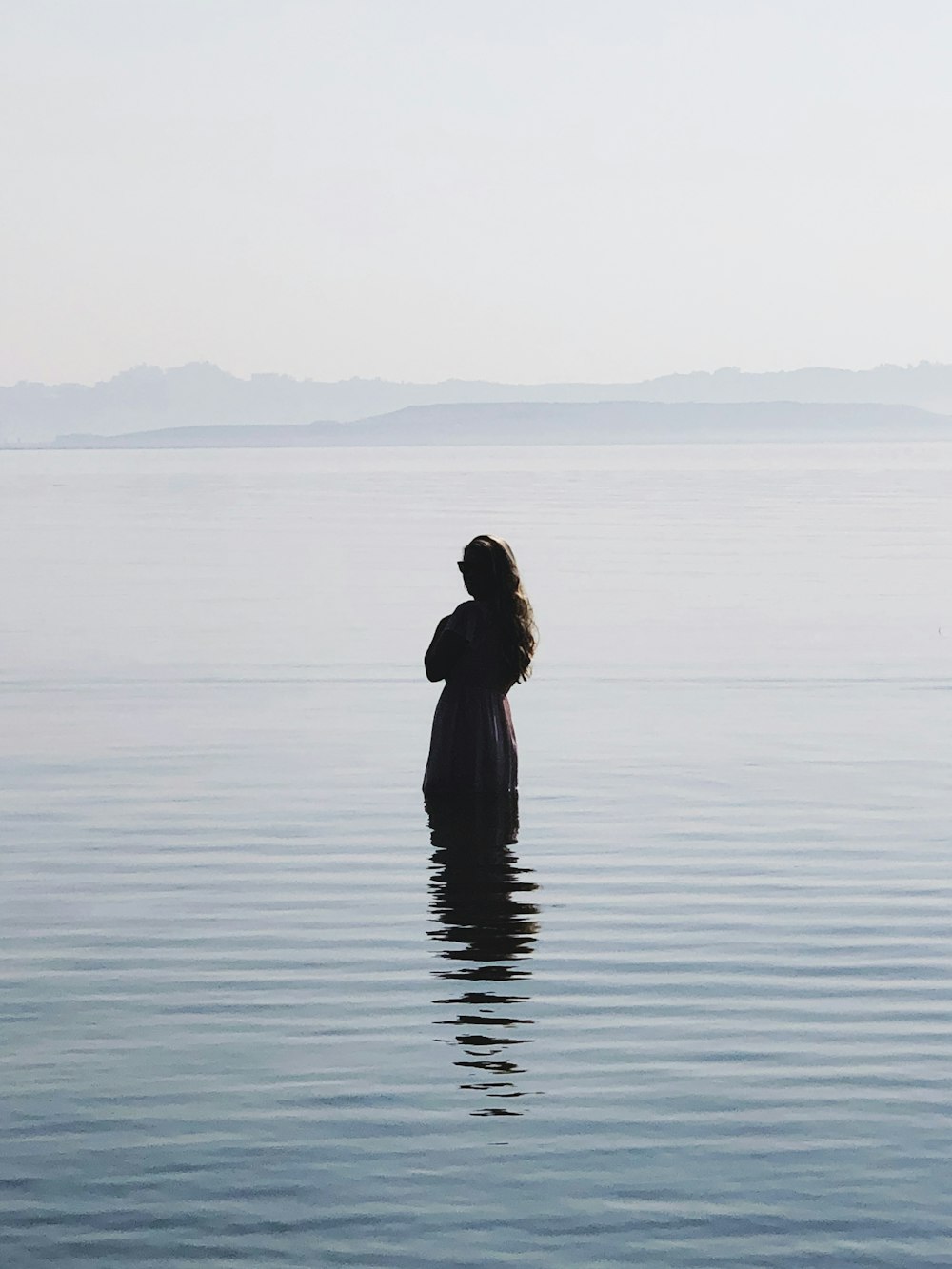 donna in vestito nero in piedi sull'acqua durante il giorno