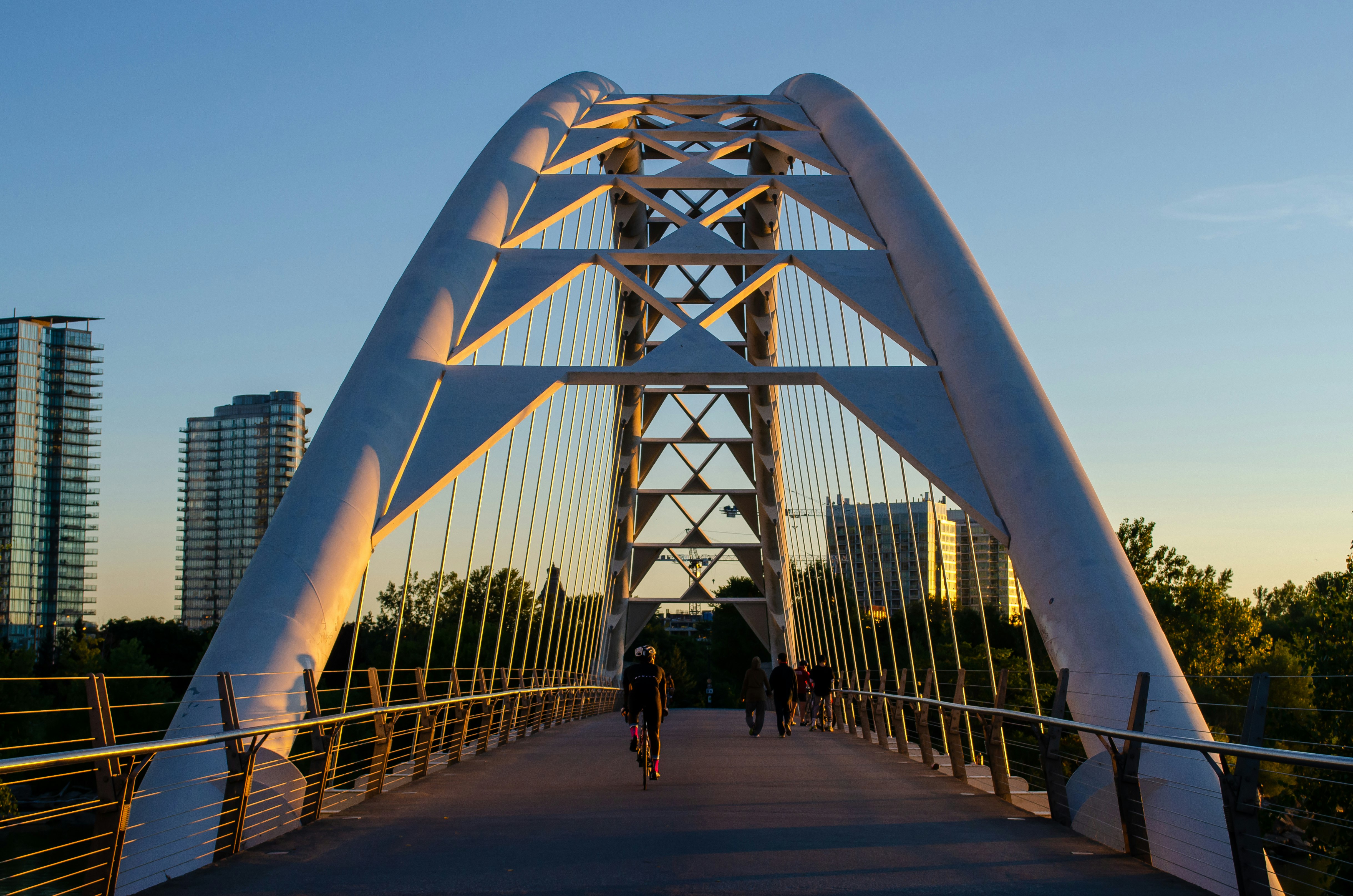 Cyclist biking through across the Humber Bay Arch Bridge in Toronto during sunrise