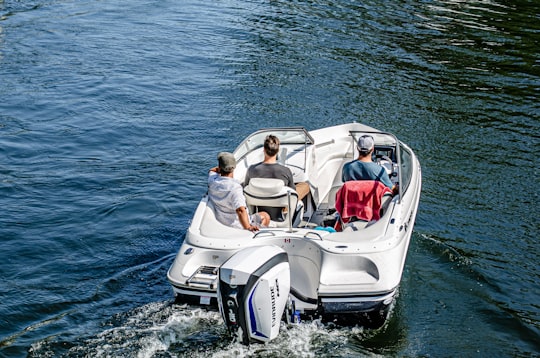 couple sitting on white and black motor boat on sea during daytime in Toronto Islands Canada