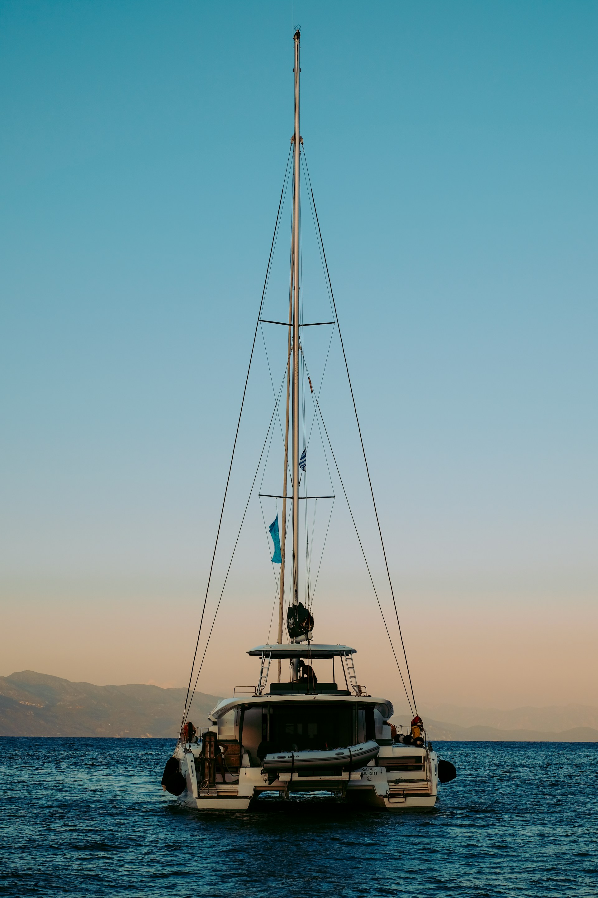 A serene catamaran sailing on crystal clear waters with a beautiful sunset in the background.