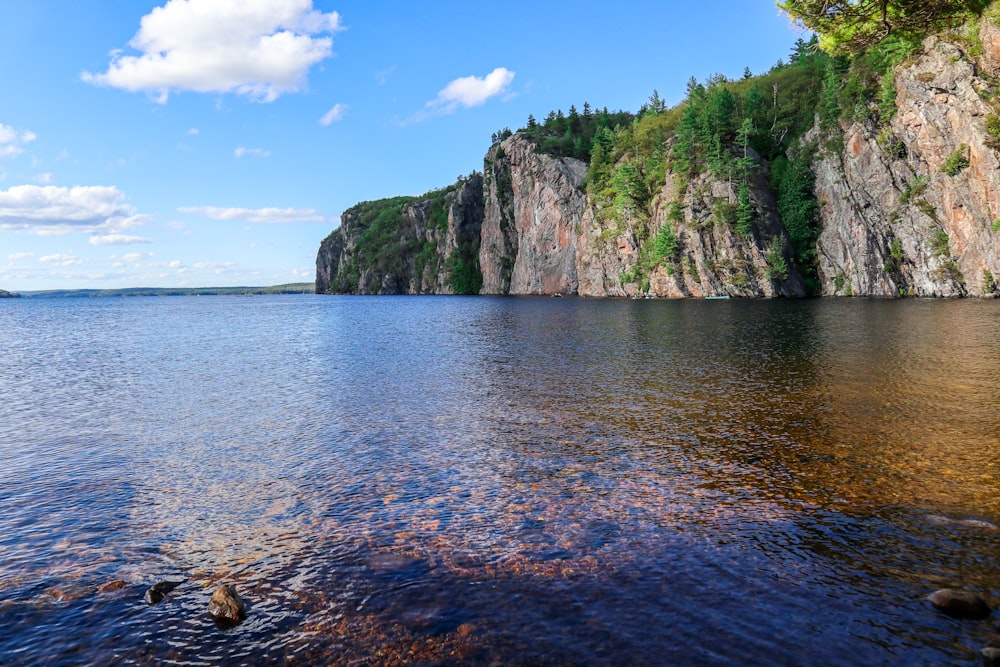 green and brown mountain beside body of water during daytime