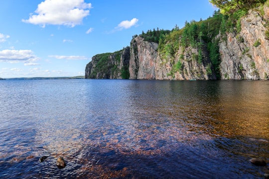 green and brown mountain beside body of water during daytime in Bon Echo Provincial Park Canada