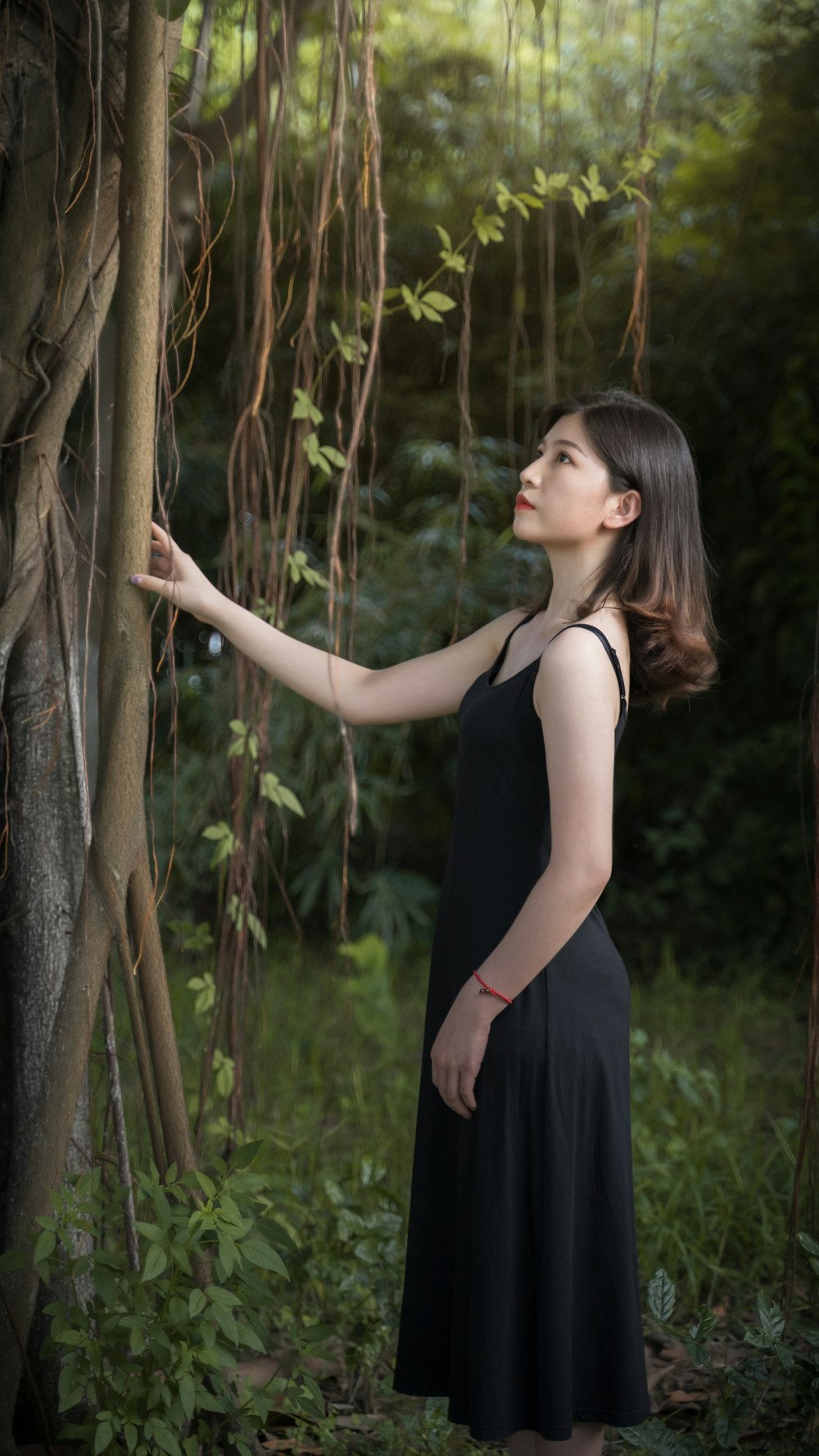 woman in black tank top standing beside brown tree trunk