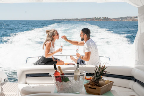 couple sitting on back of white yacht sipping champagne during daytime