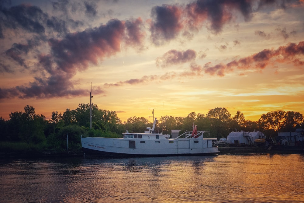 Barco blanco en el cuerpo de agua durante la puesta del sol