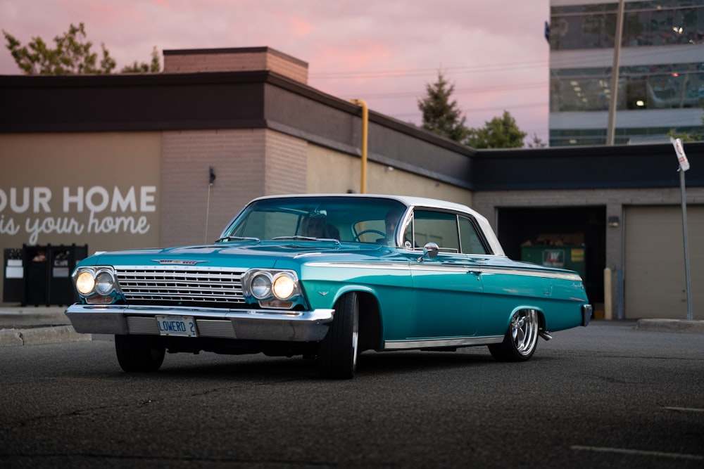 blue classic car parked near brown building during daytime