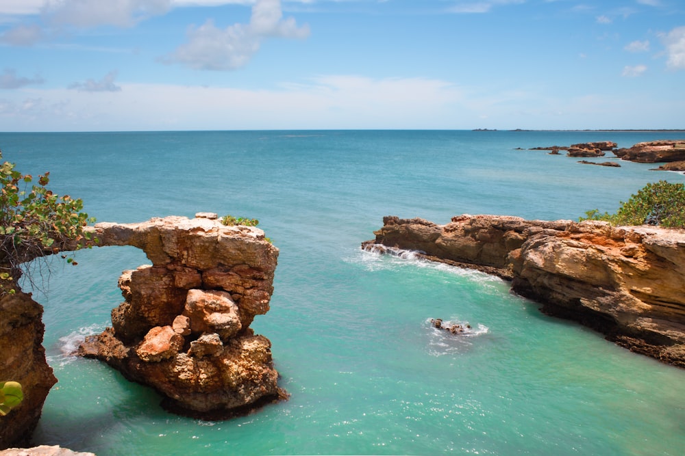 formação rochosa marrom no mar sob o céu azul durante o dia